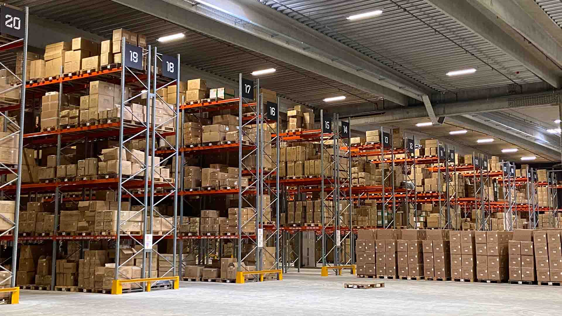 Lagerreoler fyldt med varer på Sports Group Denmarks moderne centrallager.