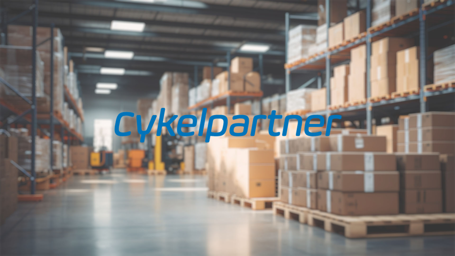Spacious warehouse interior with stacked cardboard boxes on high shelves, conveying organization. "Cykelpartner" text is overlaid in blue.
