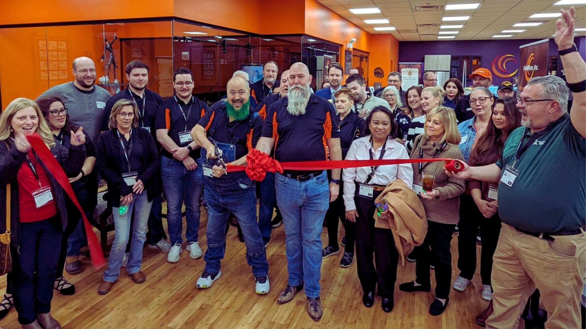 Group of people celebrating a ribbon-cutting ceremony indoors.
