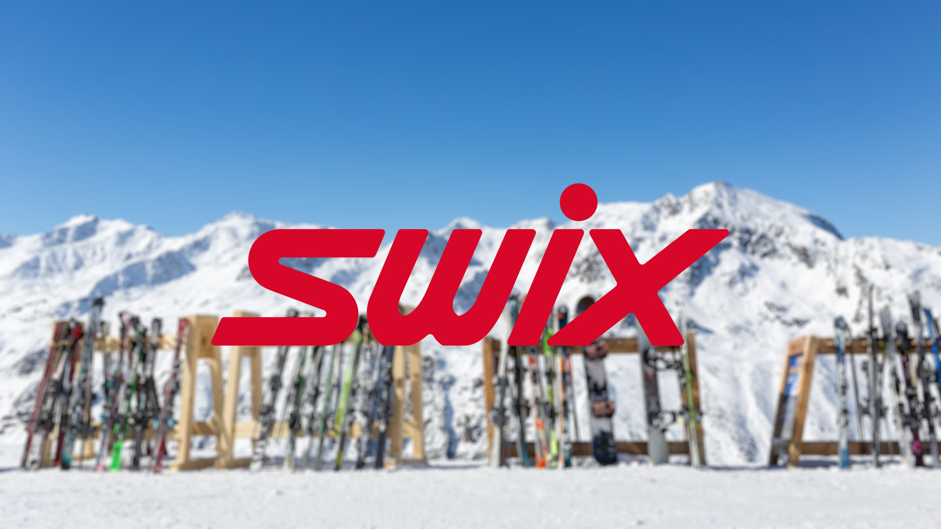 Red "Swix" logo over blurred snowy mountains and neatly arranged skis and snowboards. Bright blue sky suggests a clear, sunny winter day.
