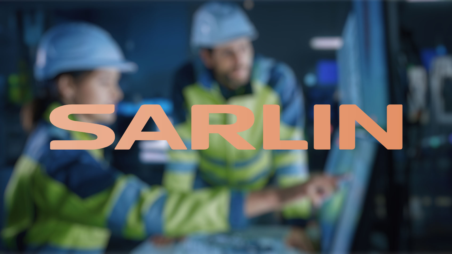 Two workers in safety gear, one pointing at a digital screen in a modern industrial setting. The logo "SARLIN" is overlaid on the image.