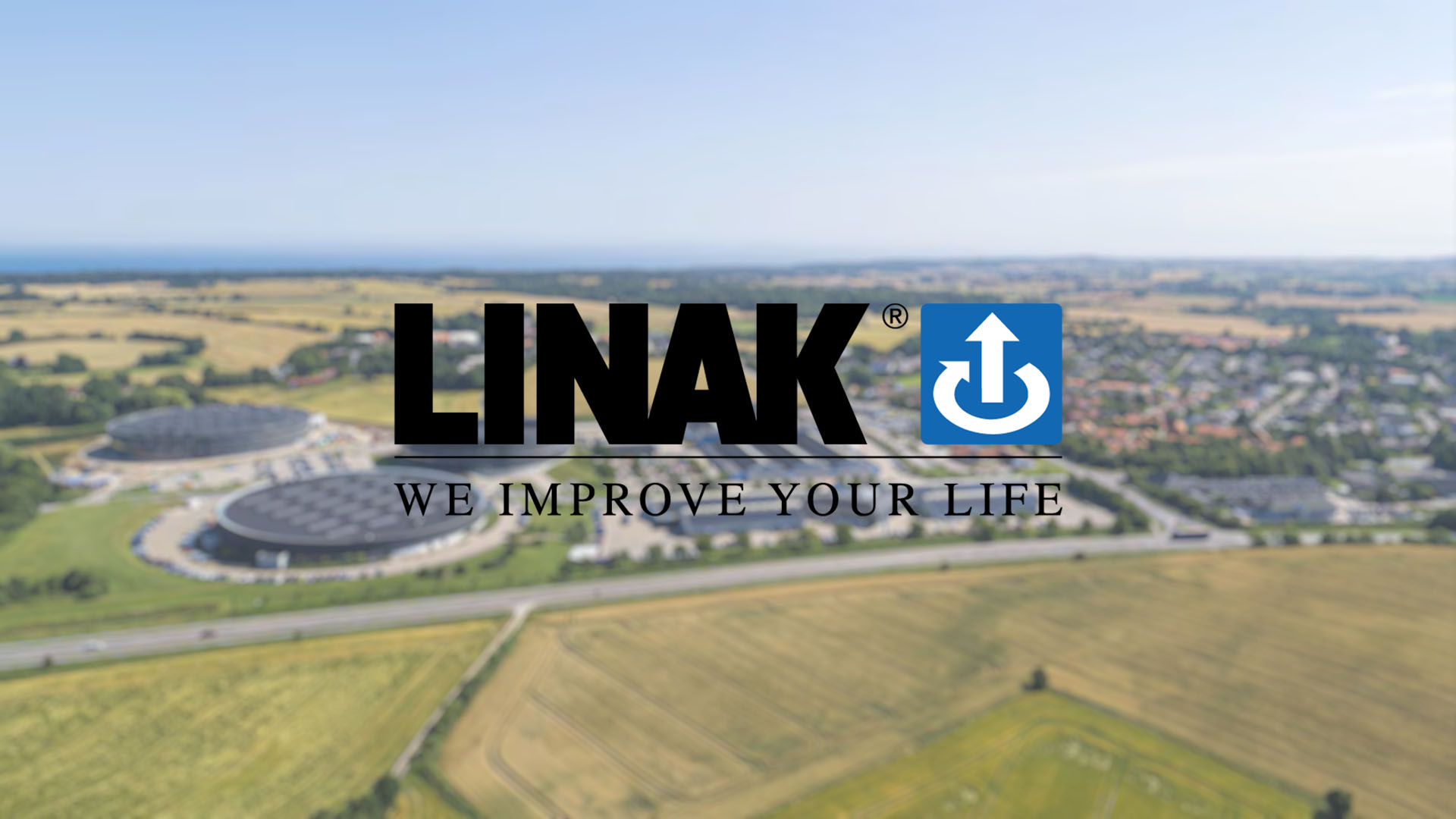 Aerial view of farmland and industry with the text "LINAK We Improve Your Life".