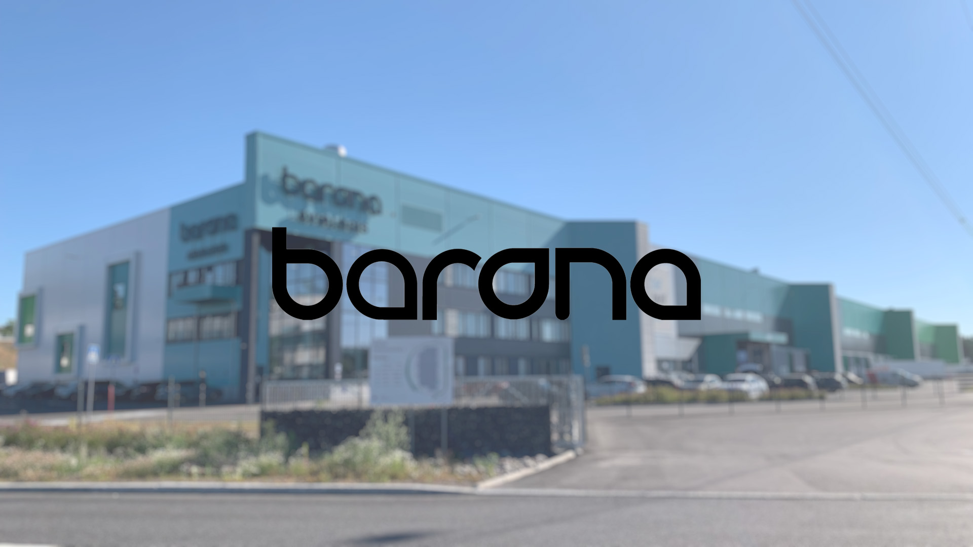 Large modern building with green accents in a sunny setting, featuring the bold black "barona" logo prominently in the center.