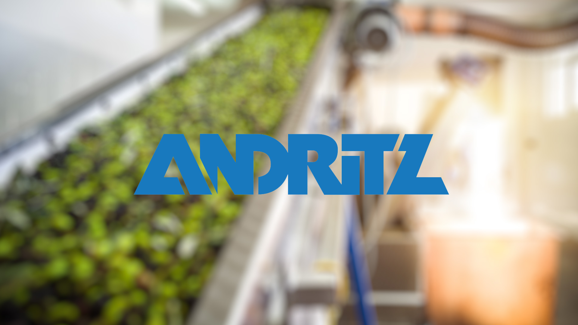Blurred image of a plant conveyor belt in a factory with bright lighting. Centered is the bold blue "ANDRITZ" logo, conveying industrial focus.