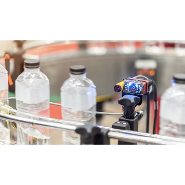 En sensor med digital skärm kontrollerar flaskor på ett rullband.